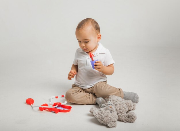 El niño juega al doctor y trata un peluche con un estetoscopio. Niños y medicina, salud. foto de estudio de alta calidad