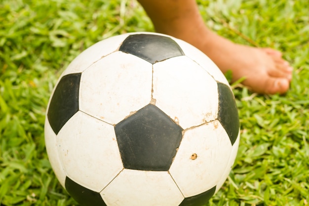 Foto niño juega al fútbol en el campo de hierba.