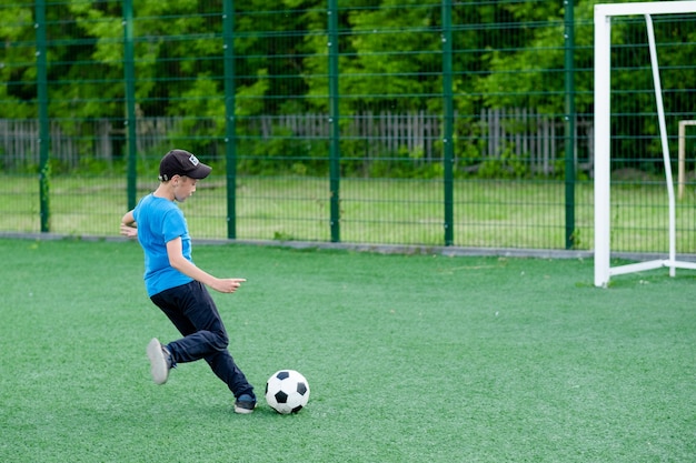 El niño juega al fútbol en el patio sobre el césped El niño patea la pelota