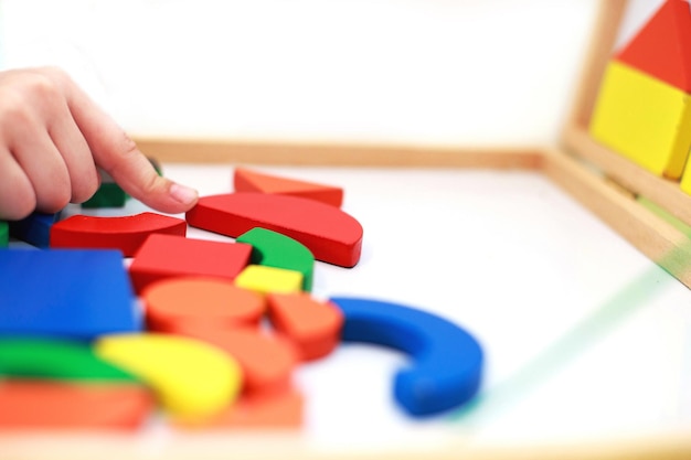 El niño juega al juego educativo magnético de madera, el niño juega con un juguete.