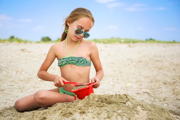 Foto niño juega con arena en la playa.