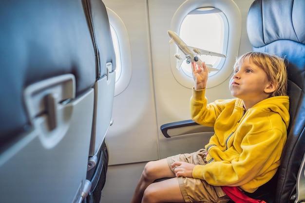 Un niño juega con un avión de juguete en el avión comercial que vuela de vacaciones