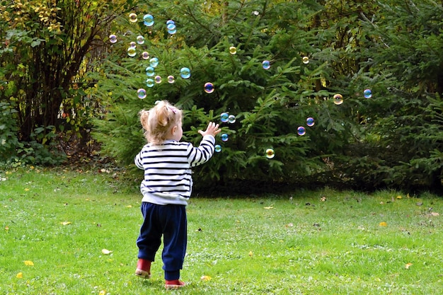 Un niño juega con burbujas en un parque.