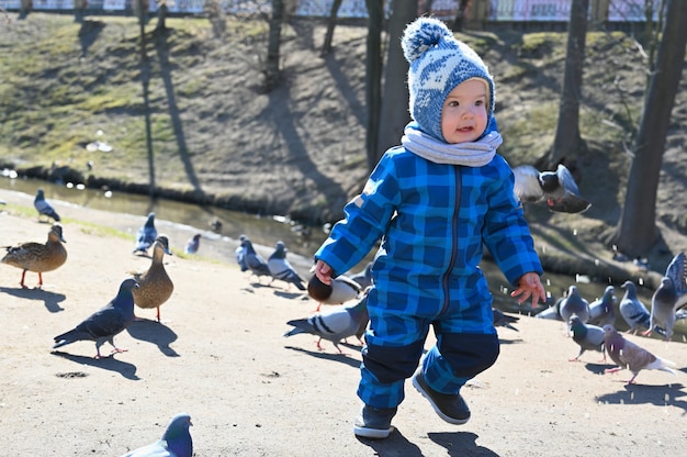 Niño juega en la calle con palomas. niño y palomas.