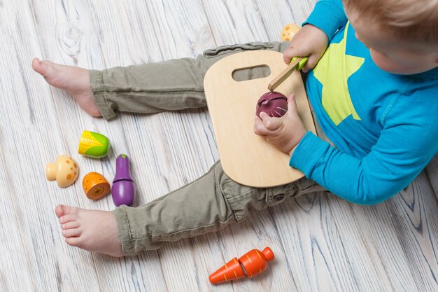 Niño juega en el chef de cerca. conjunto de verduras de madera de juguete