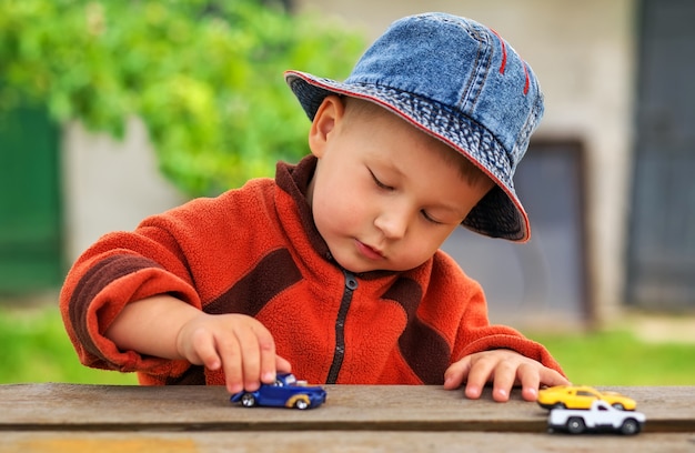 Niño juega con coloridos coches de juguete. Niño jugando con los coches cerca.