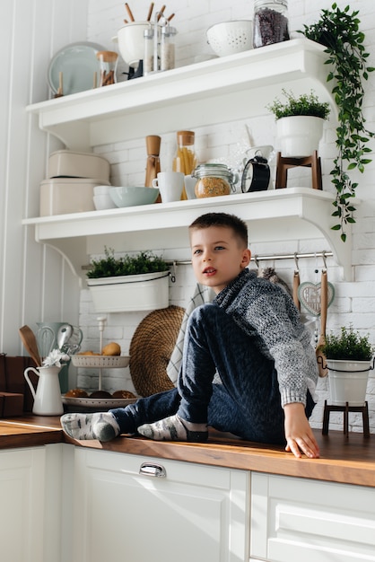 Un niño juega y desayuna en la cocina. Felicidad. Una familia.