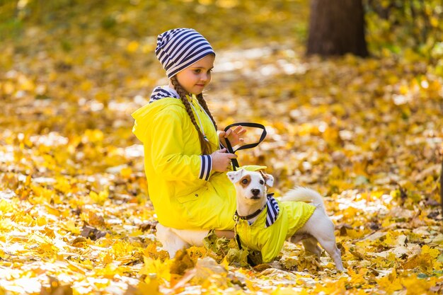 El niño juega con Jack Russell Terrier en el bosque de otoño