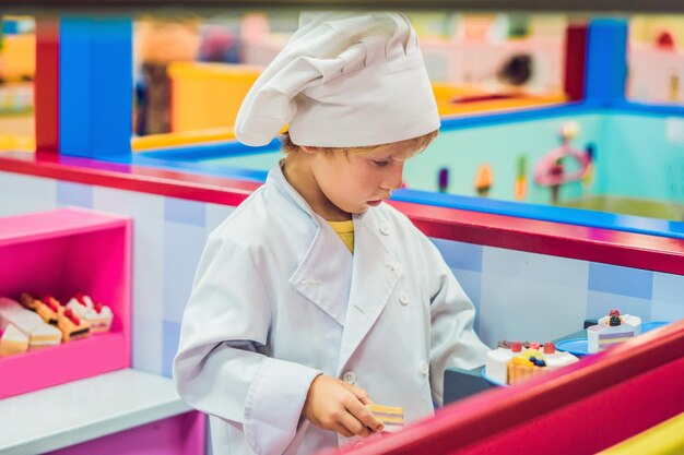 El niño juega el juego como si fuera un cocinero o un panadero en la cocina de un niño.
