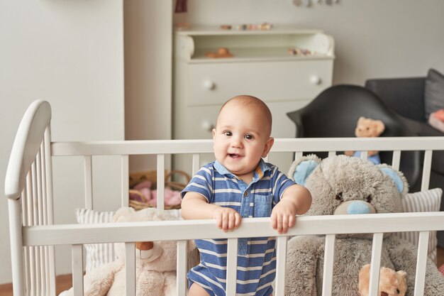 Niño juega juguetes de madera en una habitación infantil en colores brillantes, dormitorio infantil de estilo escandinavo