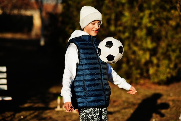 Niño juega con la pelota de fútbol en un día soleado de primavera