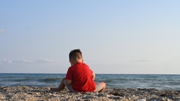 Un niño juega en la playa, con el fondo del mar.