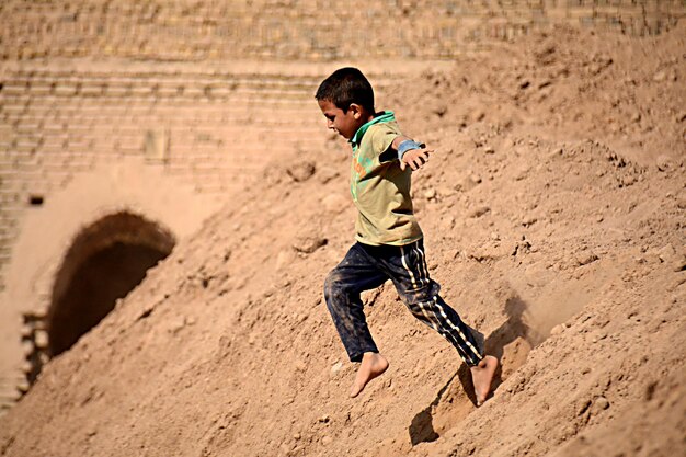 Un niño juega en un pozo de arena en el desierto.