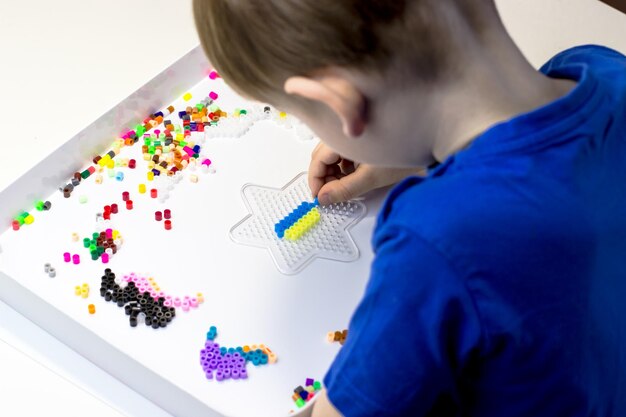 Un niño juega un termo mosaico Un niño jugando en una mesa blanca