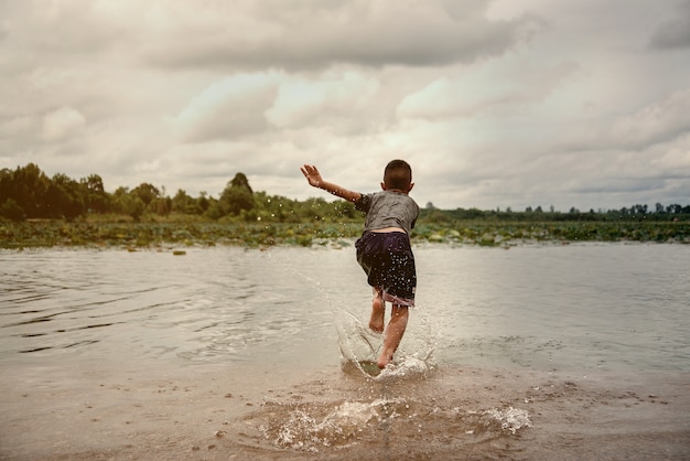 niño jugando al agua en el río