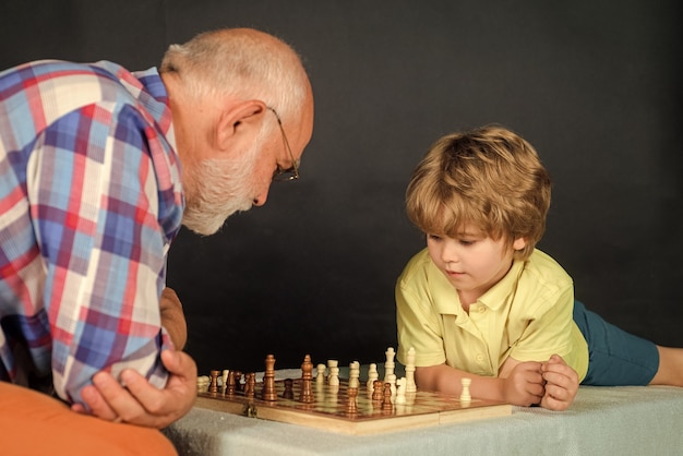 Niño jugando al ajedrez con el abuelo El abuelo y el nieto juegan al ajedrez Actividades familiares Infancia