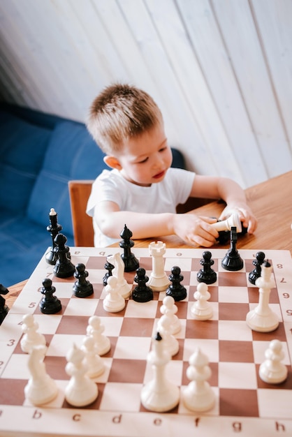 Niño jugando al ajedrez en casa en la mesa