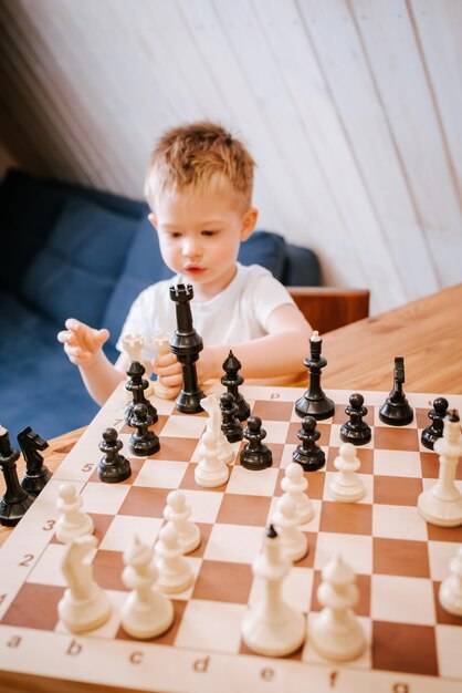 Niño jugando al ajedrez en casa en la mesa