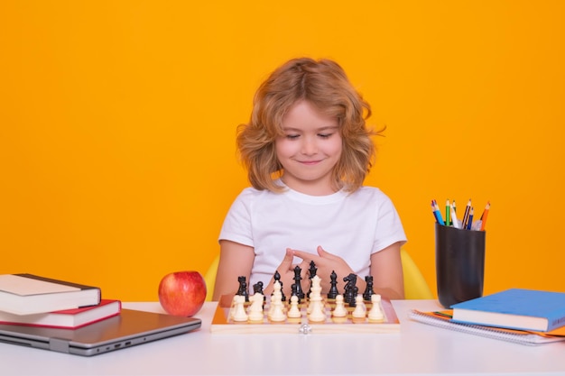 Niño jugando al ajedrez en el fondo del estudio niño jugando al Ajedrez niño inteligente pensando en el ajedrez niños temprano