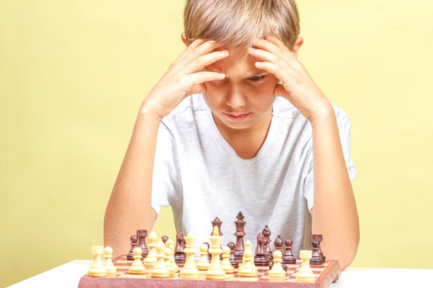 Niño jugando al ajedrez. Niño mirando el tablero de ajedrez y pensando en su estrategia.