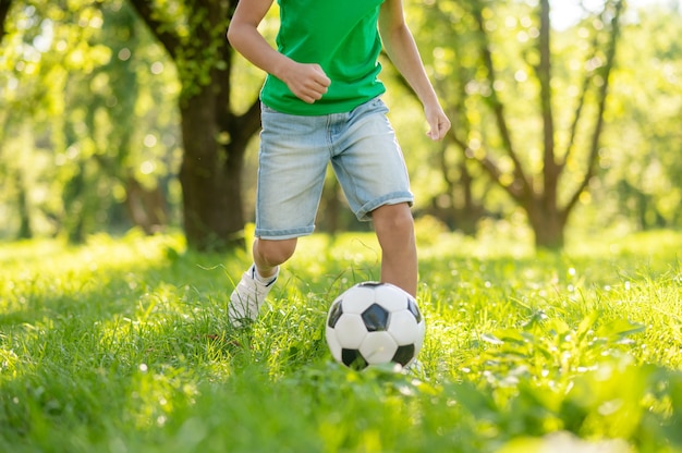 Niño jugando al fútbol en césped verde