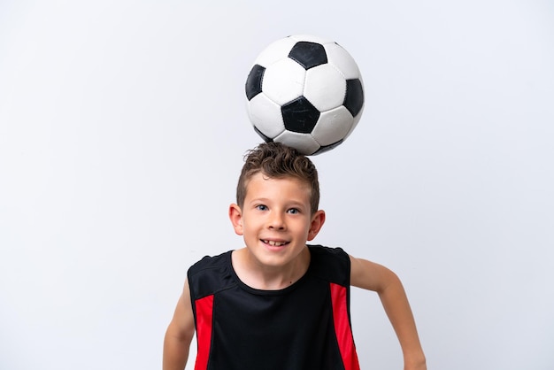 Niño jugando al fútbol sobre pared blanca aislada