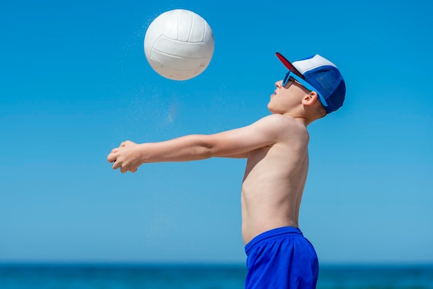 Foto niño jugando al voleibol contra el mar