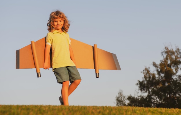 Niño jugando con alas de avión de juguete sueña con convertirse en un piloto superhéroe volando viaje de vacaciones w