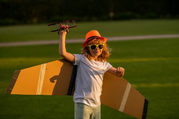 Niño jugando con alas de avión Niños de verano en el campo Recuerdos de la infancia Concepto de imaginación de sueños Niño activo jugando al aire libre