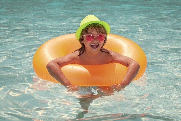 Niño jugando con anillo flotante inflable en la piscina Concepto de vacaciones de verano Retrato de niños de verano en agua de mar en la playa