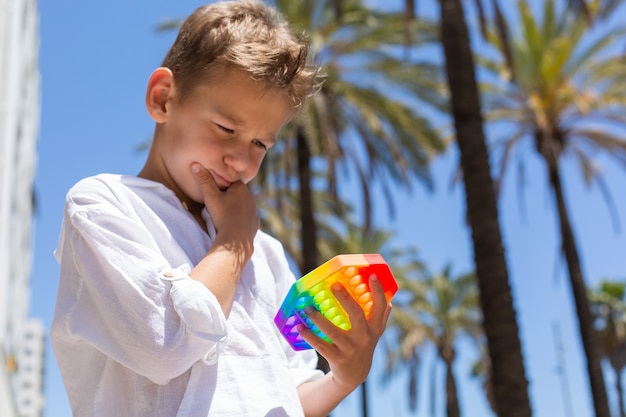 Niño jugando con arco iris anti estrés pop it juguete al aire libre