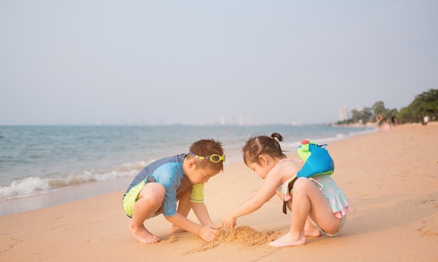 niño jugando arena en la playa, niños jugando en el mar