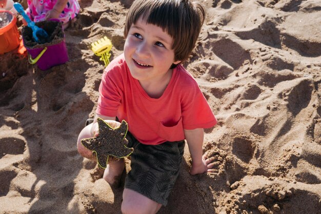 Niño jugando con arena en la playa