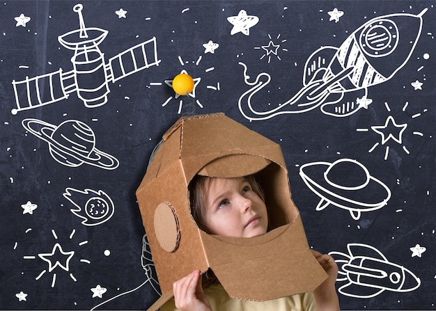 Foto niño jugando a astronauta con caja de cartón como casco
