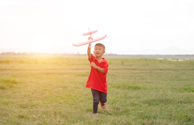 Foto niño jugando avión de cartón