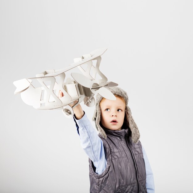 Niño jugando con avión de juguete de papel y soñando con convertirse en piloto