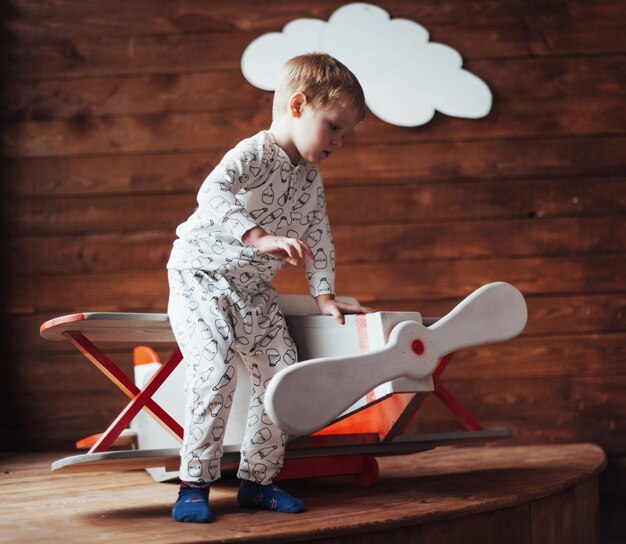 niño jugando con avión de madera