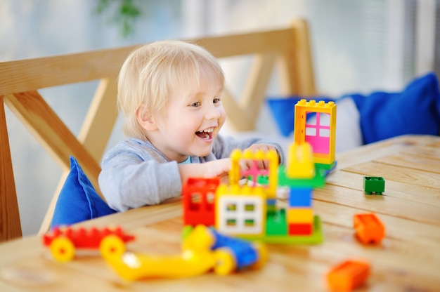 Niño jugando con bloques de plástico de colores en el jardín de infantes o en casa