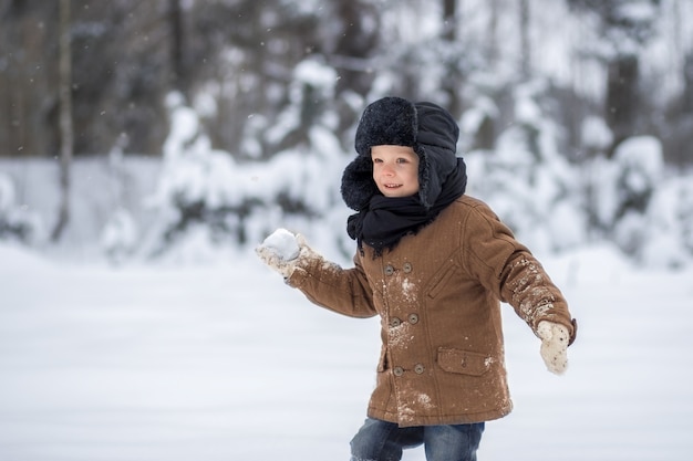 niño jugando bolas de nieve en invierno