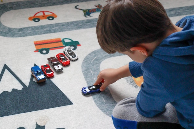 Foto niño jugando con un coche de juguete en una alfombra de juego