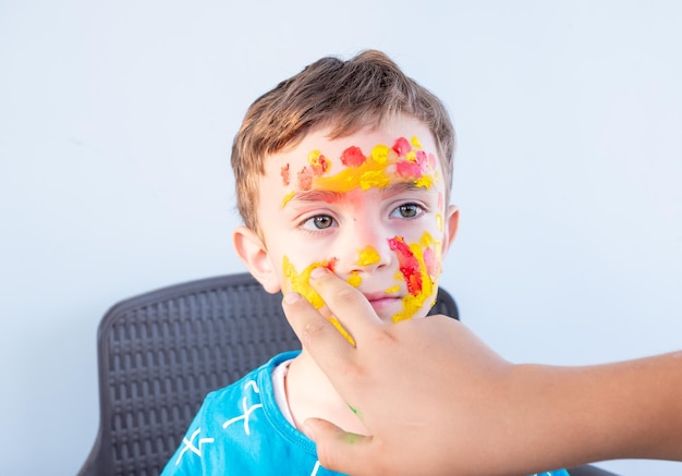 Niño jugando con colores usando sus manos y su cara.