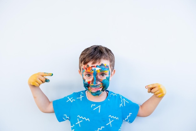 Niño jugando con colores usando sus manos y su cara.