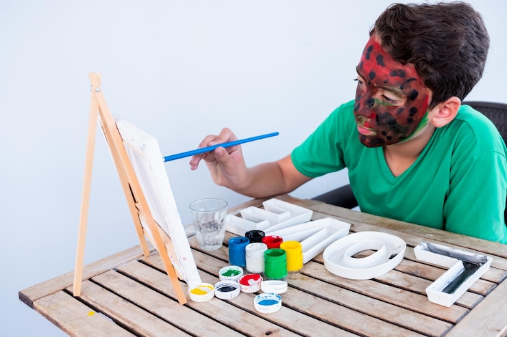 Foto niño jugando con colores usando sus manos y su cara.