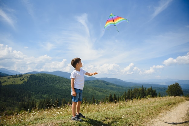 Niño jugando con una cometa en las montañas