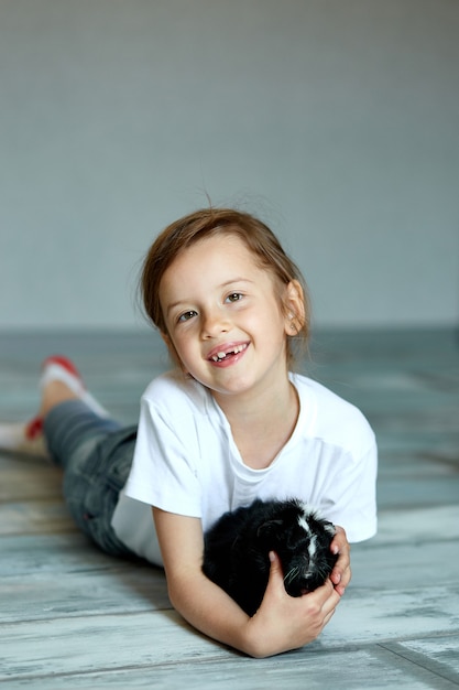 Niño jugando con conejillo de indias. Niña cuida de mascotas.