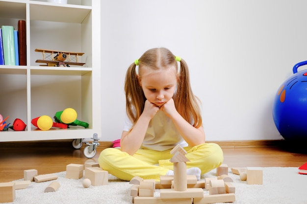 Niño jugando cubos en el piso. Chica está pensando