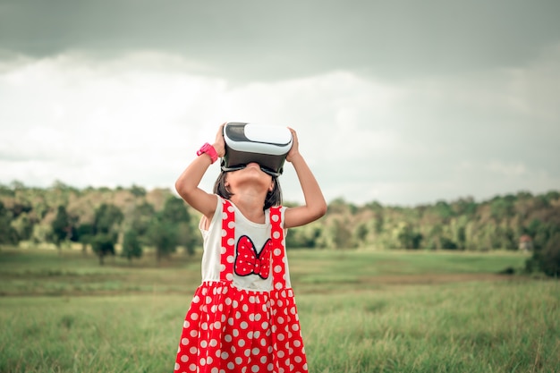 Niño jugando con divertidas gafas de realidad visual o tecnología de realidad virtual en una hermosa naturaleza de pradera