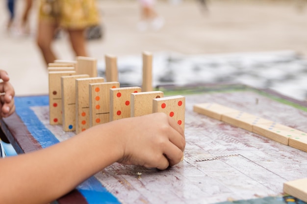 Niño jugando con dominó de madera afuera