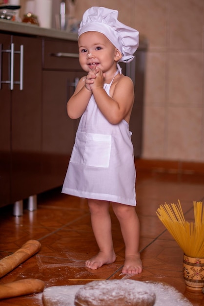 niño jugando con harina en la cocina vestido de cocinero