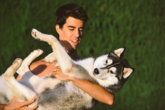 Niño jugando con husky siberiano levantando en sus brazos.